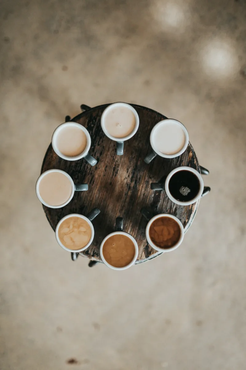 Different types of coffee drinks in mugs on a round table