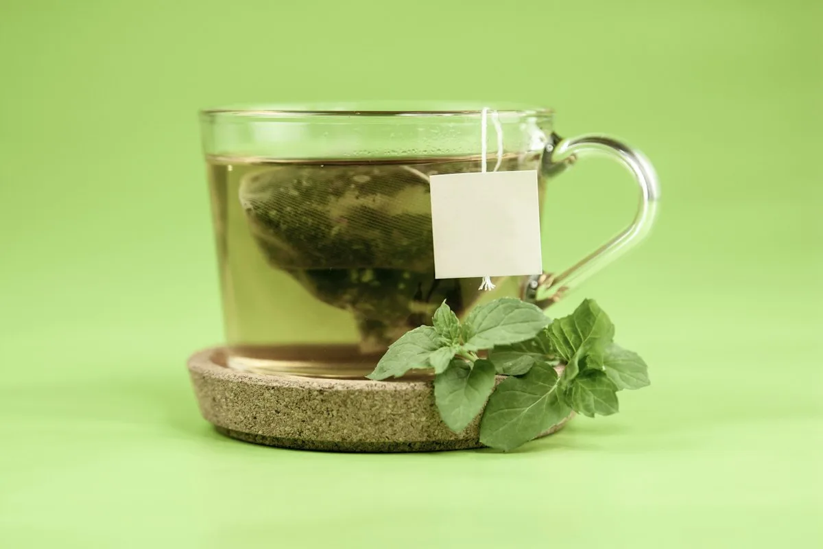 Green tea in a glass cup with fresh leaves