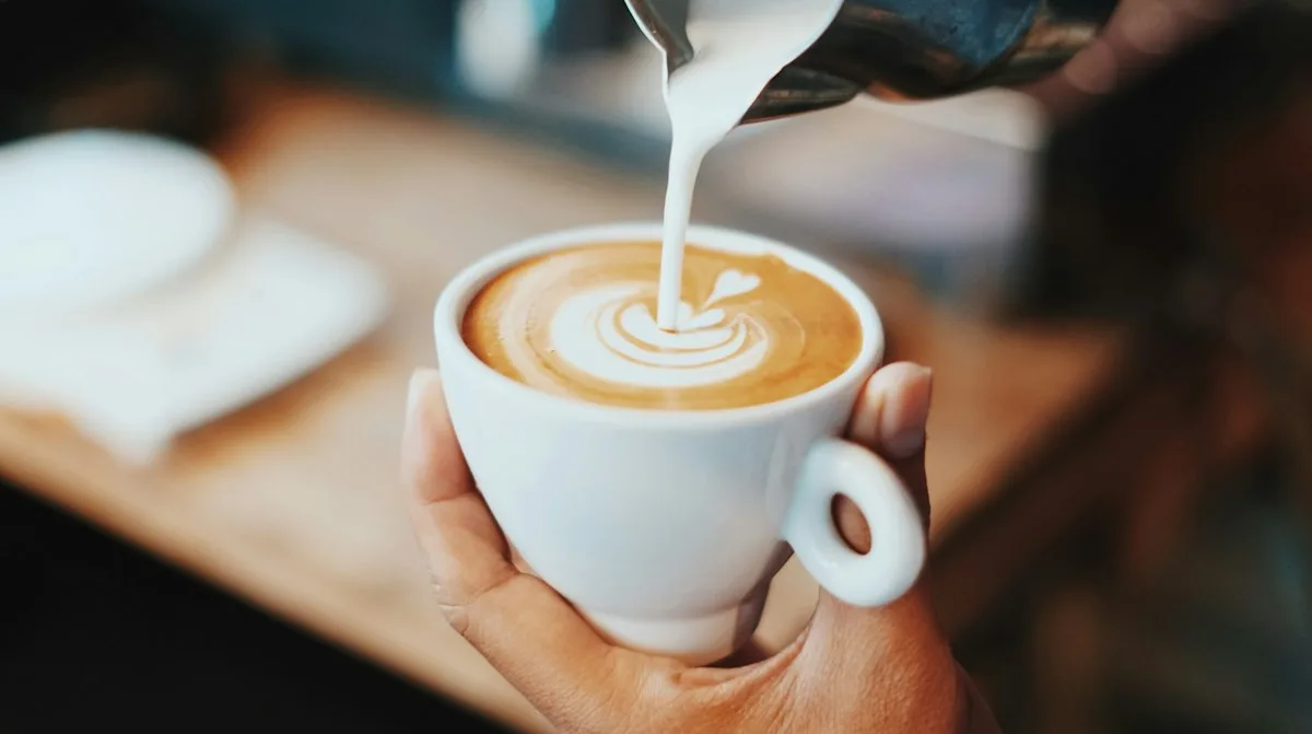 Latte coffee with steamed milk being poured