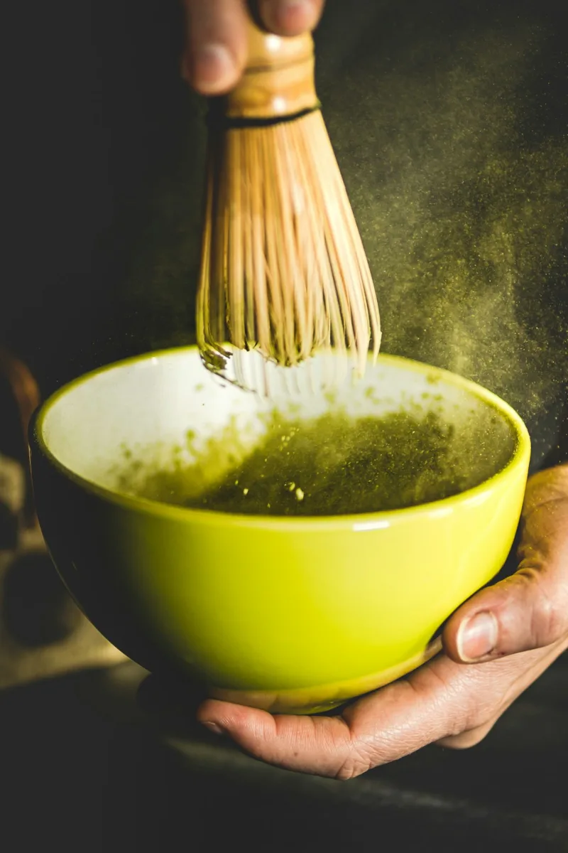Matcha tea being whisked in a bowl